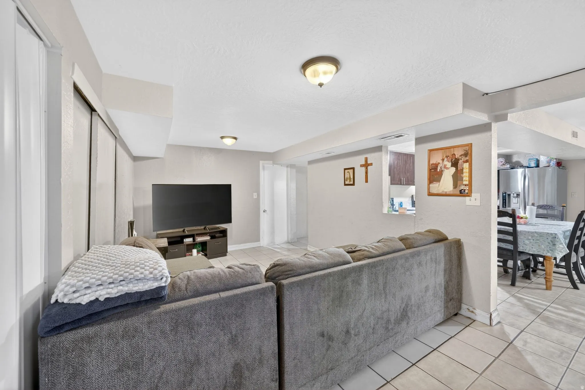 Open-concept living area featuring light-toned walls and tile flooring