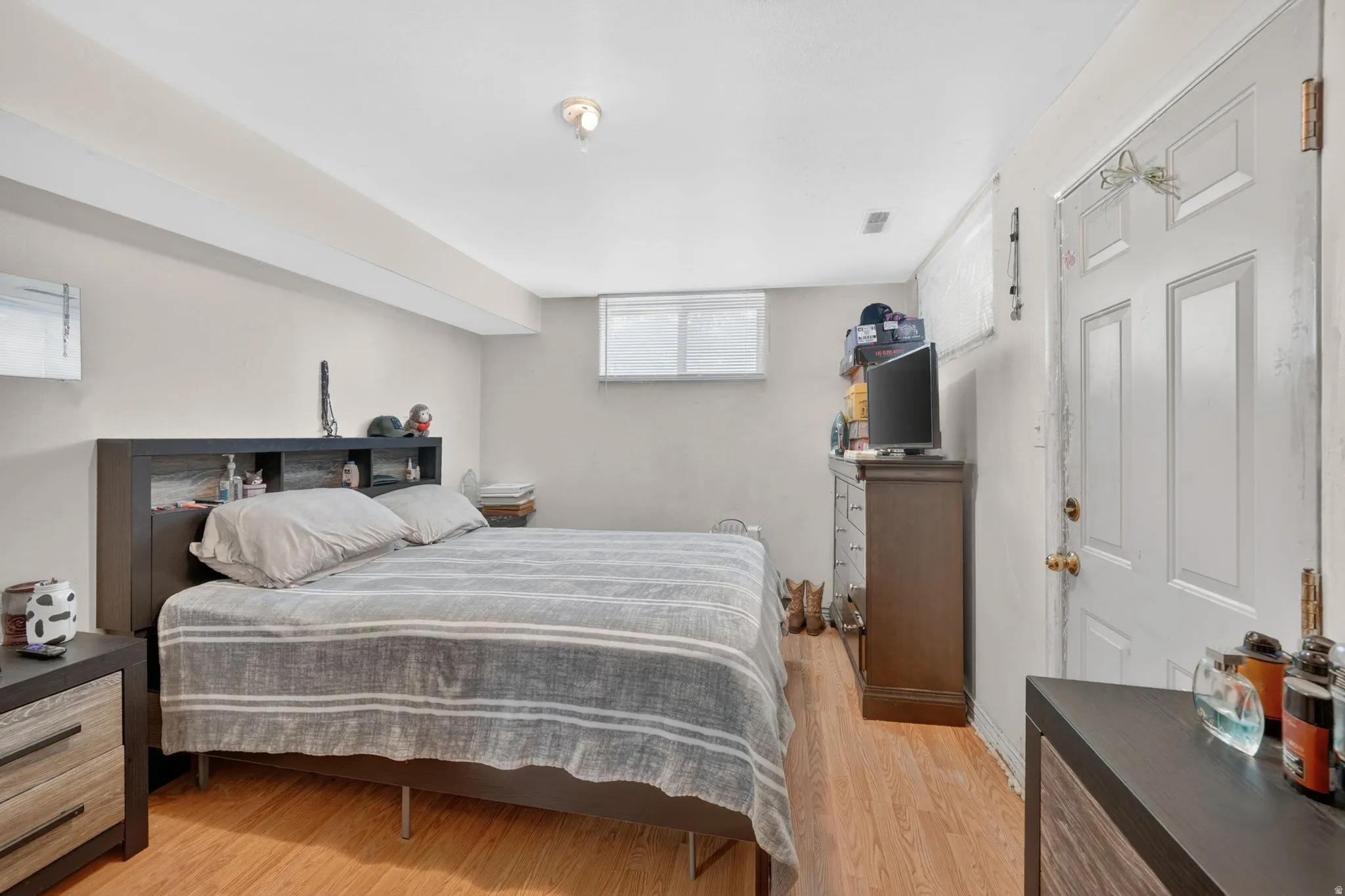 Room featuring wood-finish flooring, light-toned walls, and a white ceiling with exposed beams