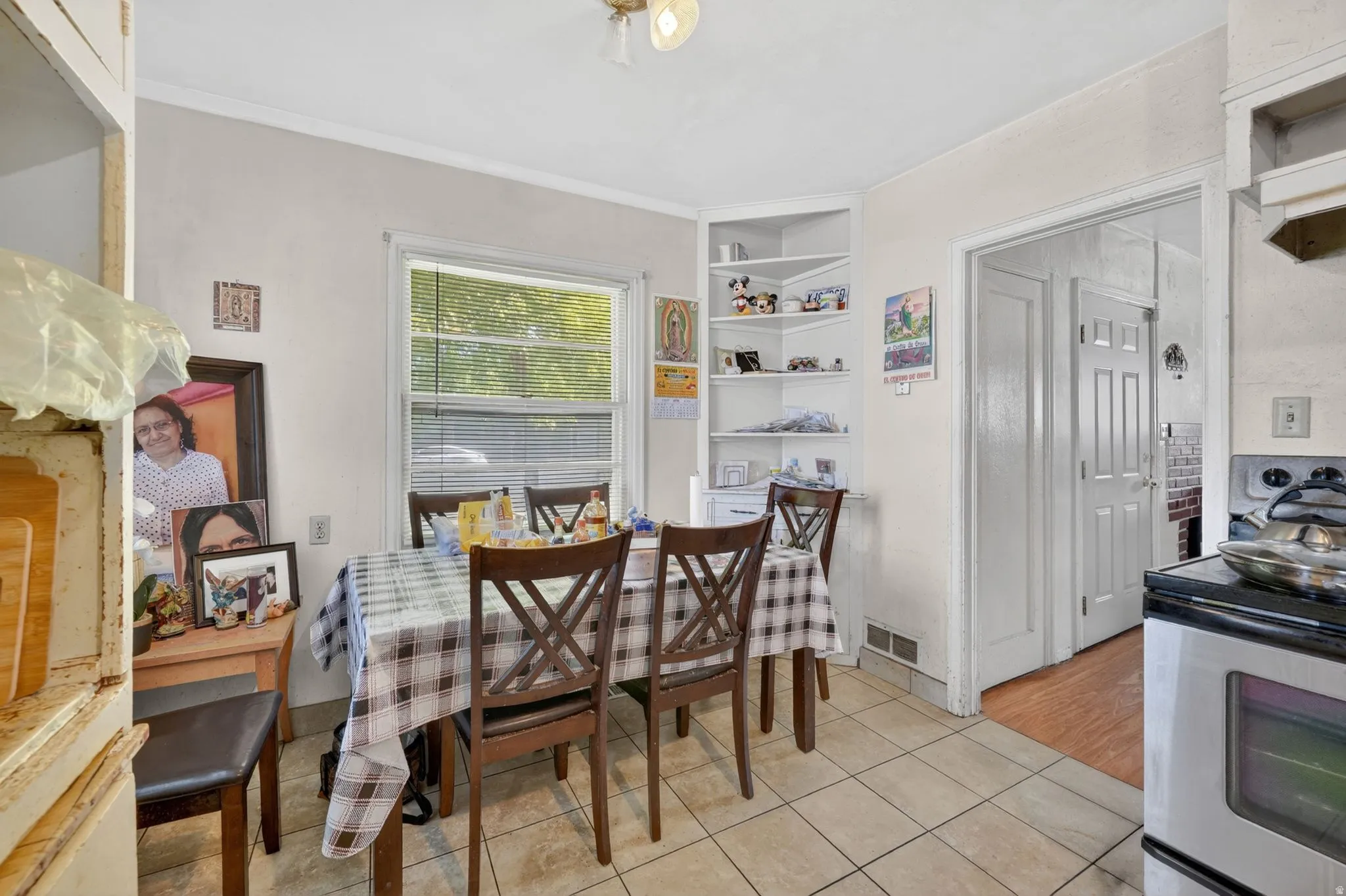 Kitchen dining area featuring tile flooring, a double-hung window, and a built-in corner shelving unit