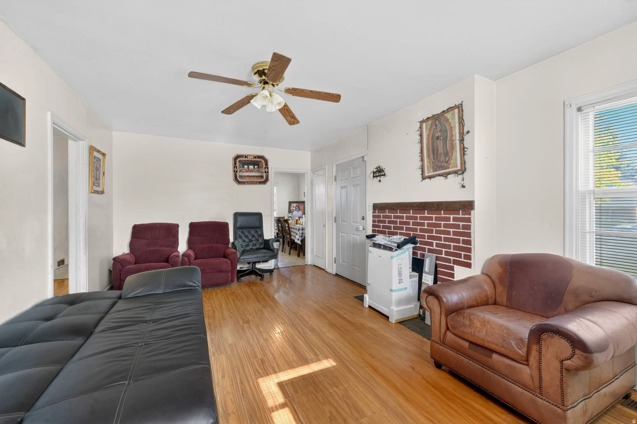 Spacious living area featuring wood-finish flooring, light neutral wall paint, and a ceiling fan