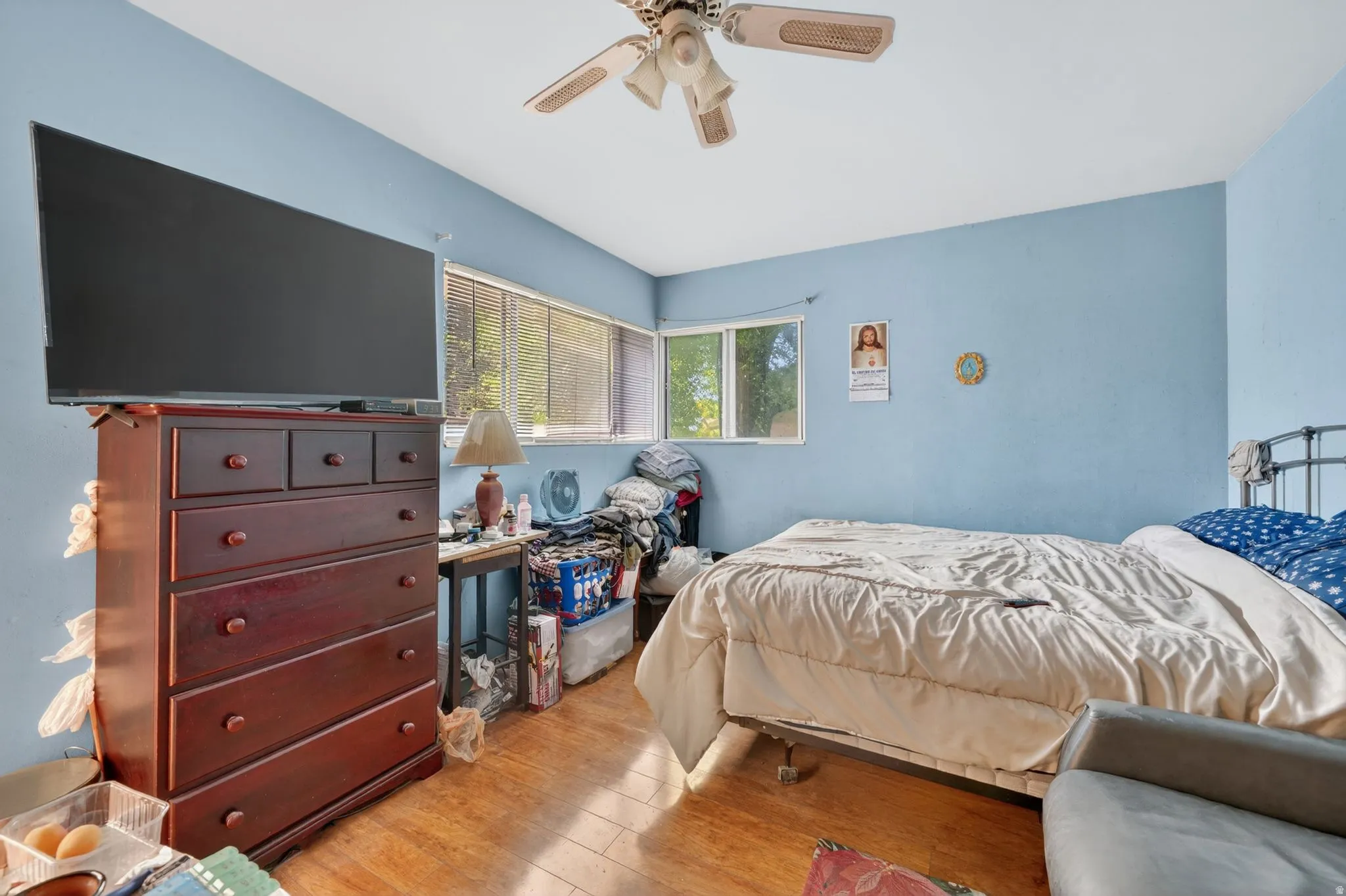 Room featuring wood-finish flooring, a ceiling fan with light fixture, and horizontal windows