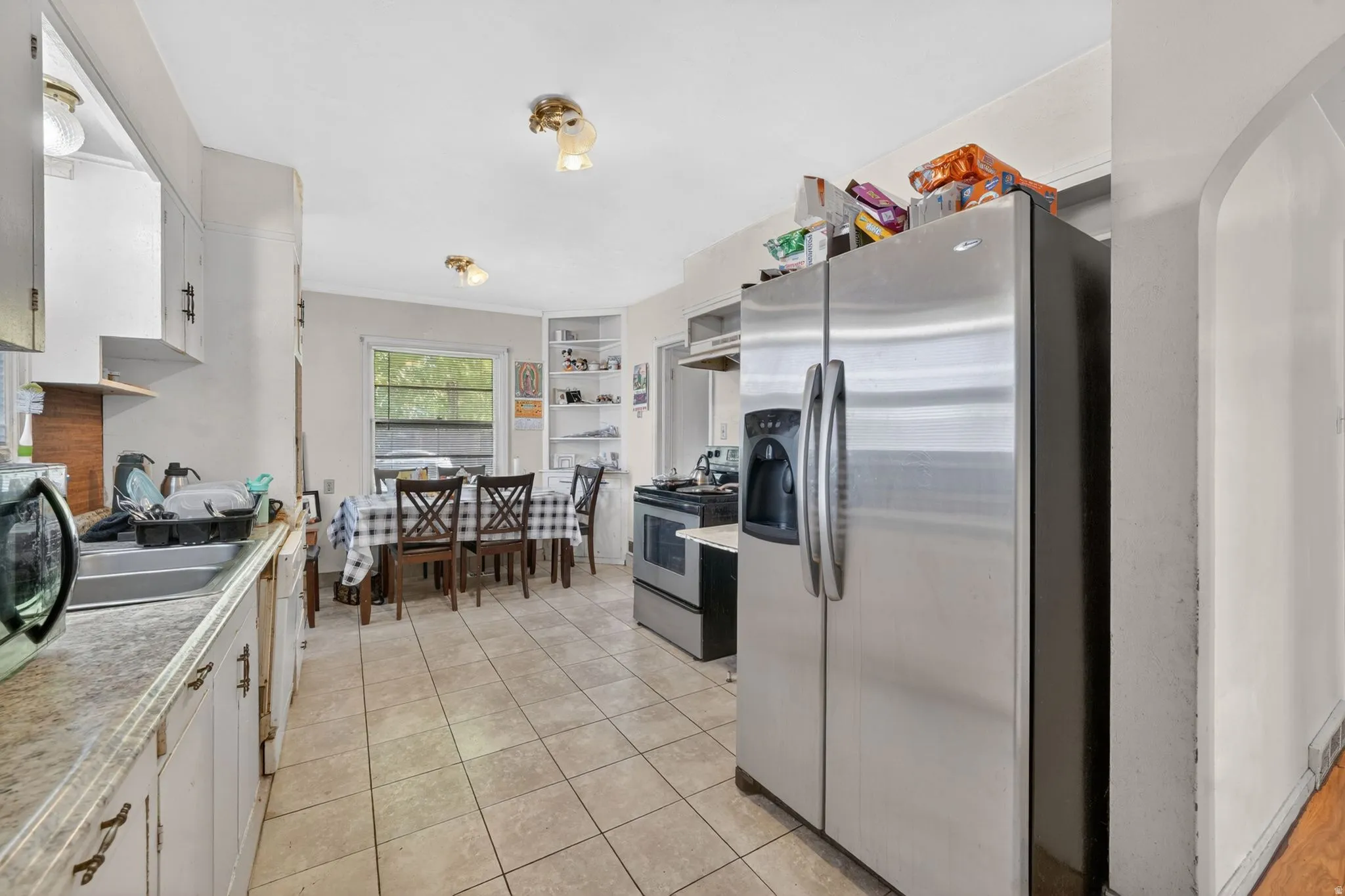 Kitchen with ceramic tile flooring, white cabinetry, and a double-door stainless steel refrigerator