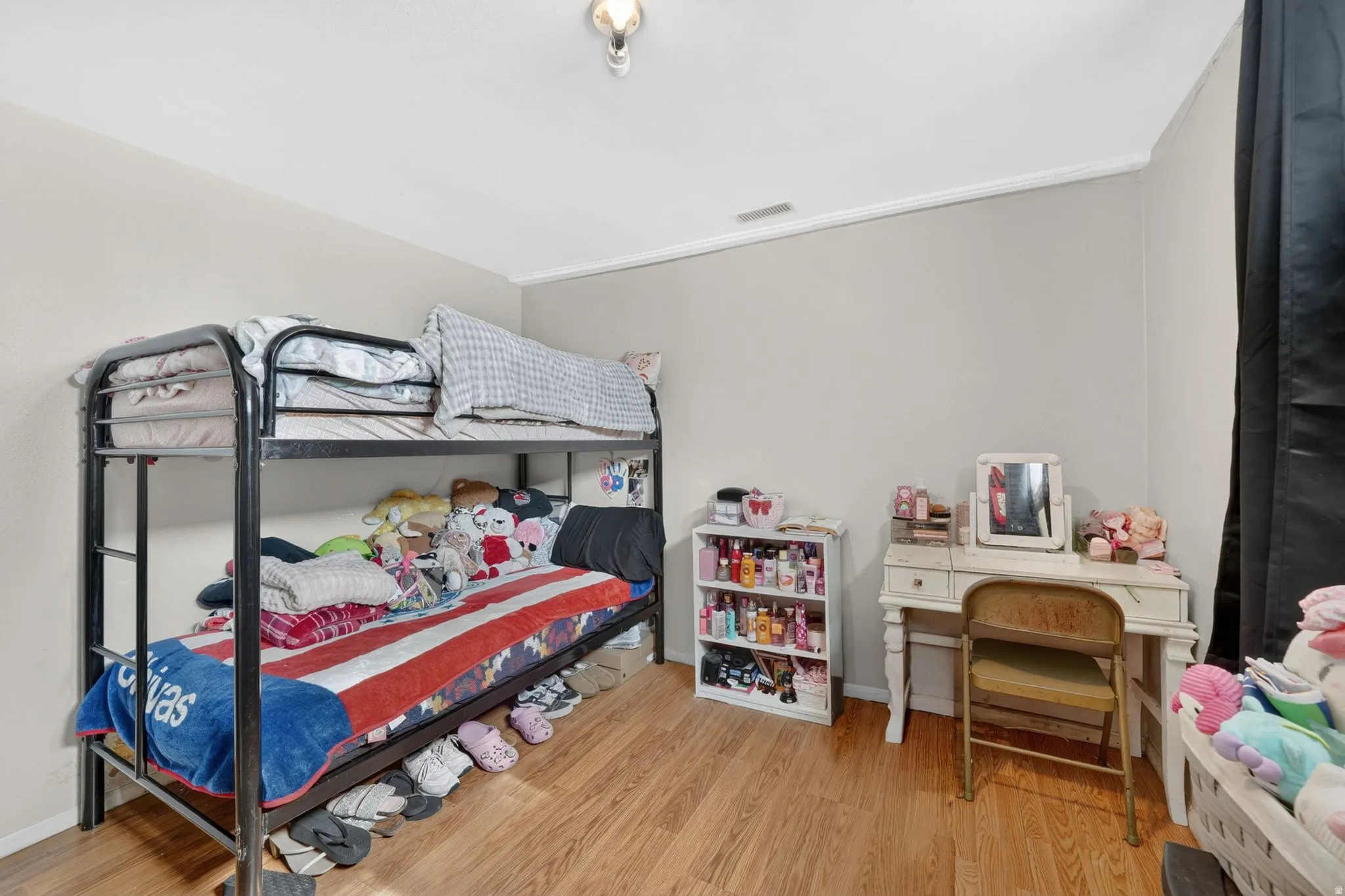 Room featuring wood-finish flooring, light neutral wall paint, and white crown molding