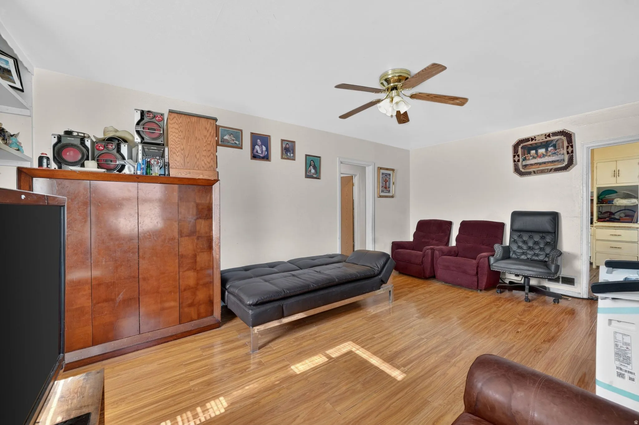 Bright interior room featuring wood-finish flooring, a ceiling fan with integrated lighting, and neutral wall tones