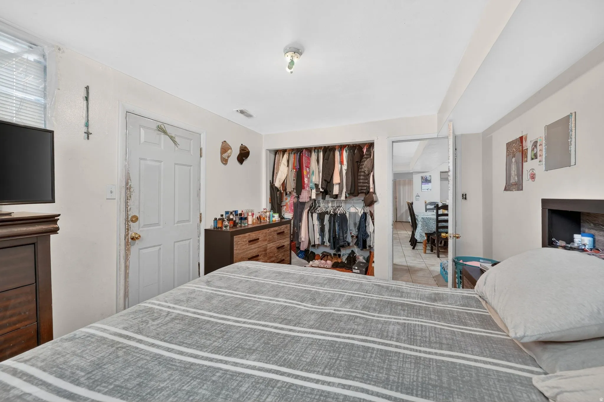 Interior space featuring a built-in open closet, a ceiling-mounted light fixture, and a window with horizontal blinds