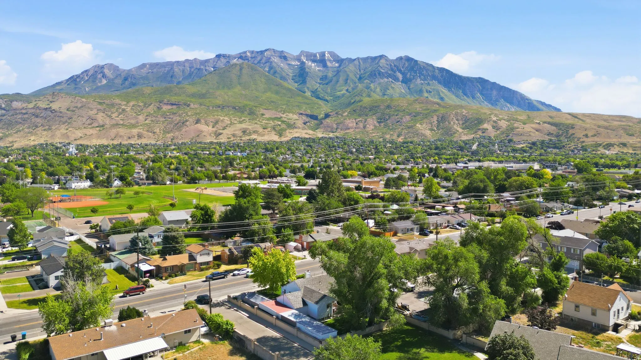 Expansive neighborhood with mature trees and established residences, featuring a large community park with athletic fields