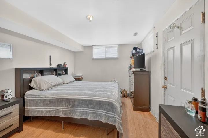 Room featuring wood-finish flooring, light-toned walls, and a white ceiling with exposed beams