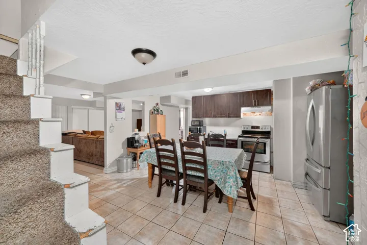 Kitchen and dining area featuring tile flooring, dark wood cabinetry, a stainless steel refrigerator, and a stainless steel range with overhead microwave