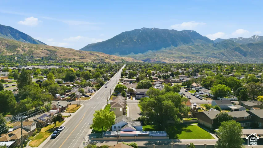 Expansive neighborhood with mature trees, a prominent paved road, and distant mountains