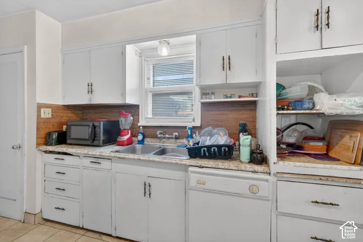 Kitchen featuring wood-finish backsplash, white cabinetry with bronze hardware, and a stainless steel double basin sink