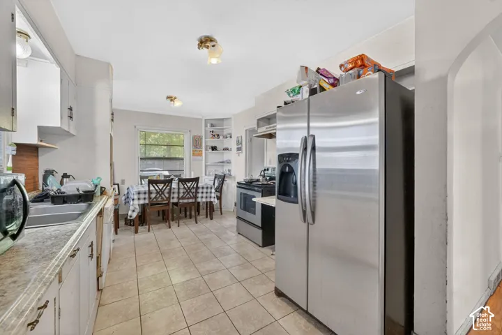 Kitchen with ceramic tile flooring, white cabinetry, and a double-door stainless steel refrigerator