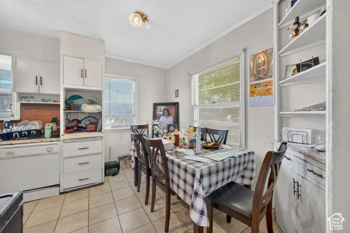 Kitchen area featuring tile flooring, white cabinetry, a built-in dishwasher, and multiple windows
