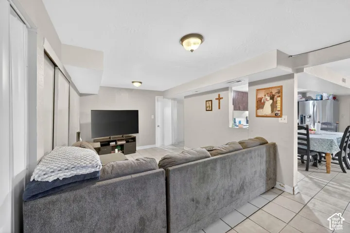 Open-concept living area featuring light-toned walls and tile flooring