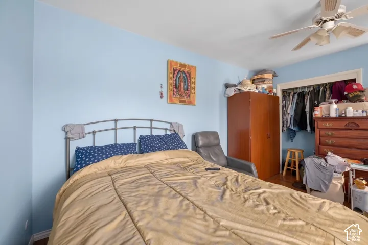 Bedroom featuring light blue walls, wood-finish flooring, a ceiling fan, and a built-in closet with an open doorway