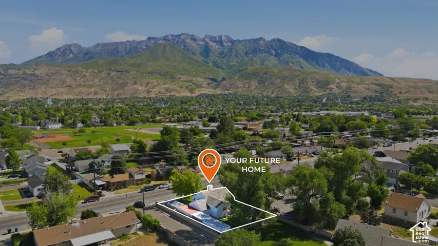Aerial perspective showcasing a residential property with a mountain backdrop, surrounded by established trees and a neighborhood setting