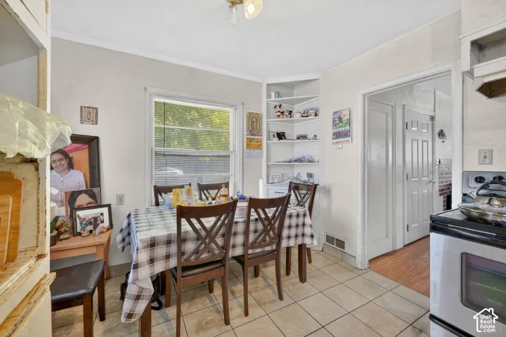 Kitchen dining area featuring tile flooring, a double-hung window, and a built-in corner shelving unit