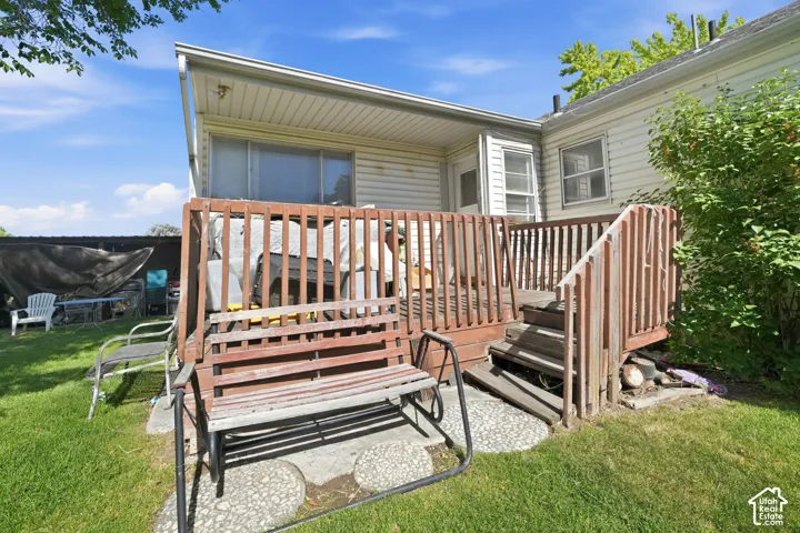 Elevated wooden deck with stairs providing access to the grassy yard