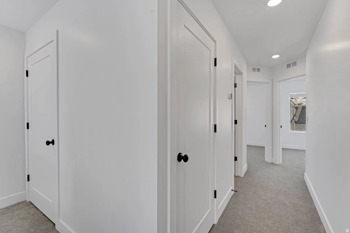 Hallway featuring recessed lighting, light gray carpet flooring, white walls, white trim, and matte black door hardware