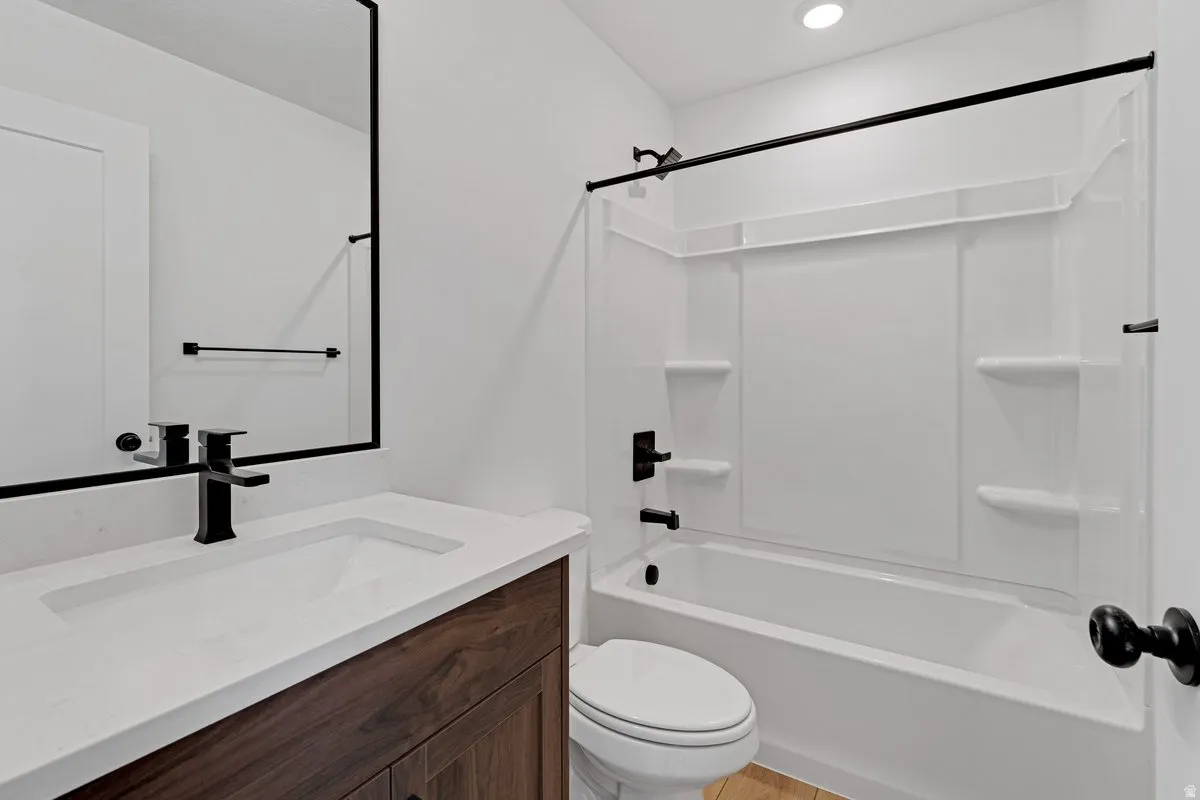 Bathroom featuring a wood-finish vanity with an integrated white sink, a matte black faucet, and a wall-mounted mirror
