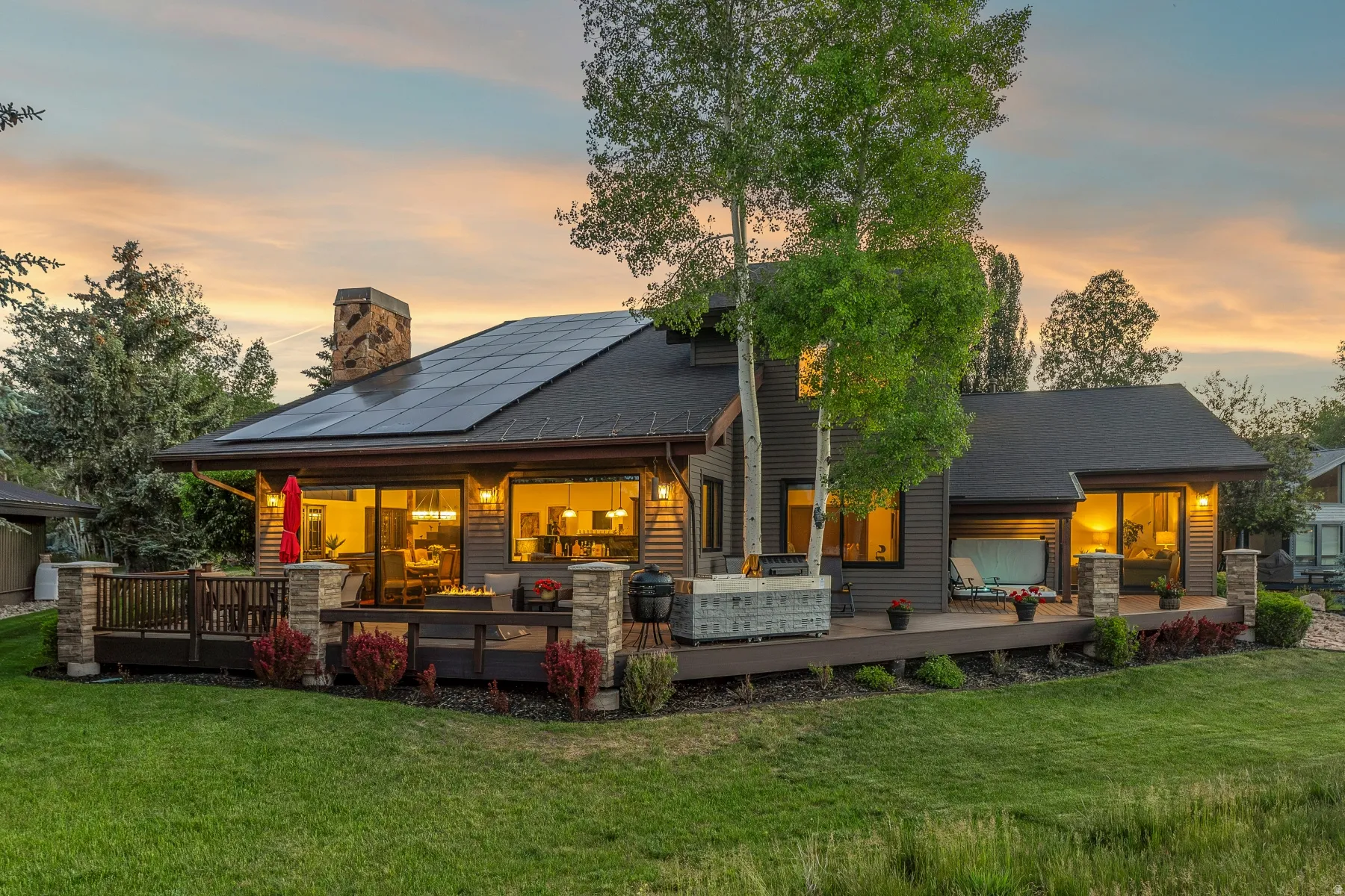 Expansive rear deck featuring a built-in spa, stone pillar accents, and a stone chimney