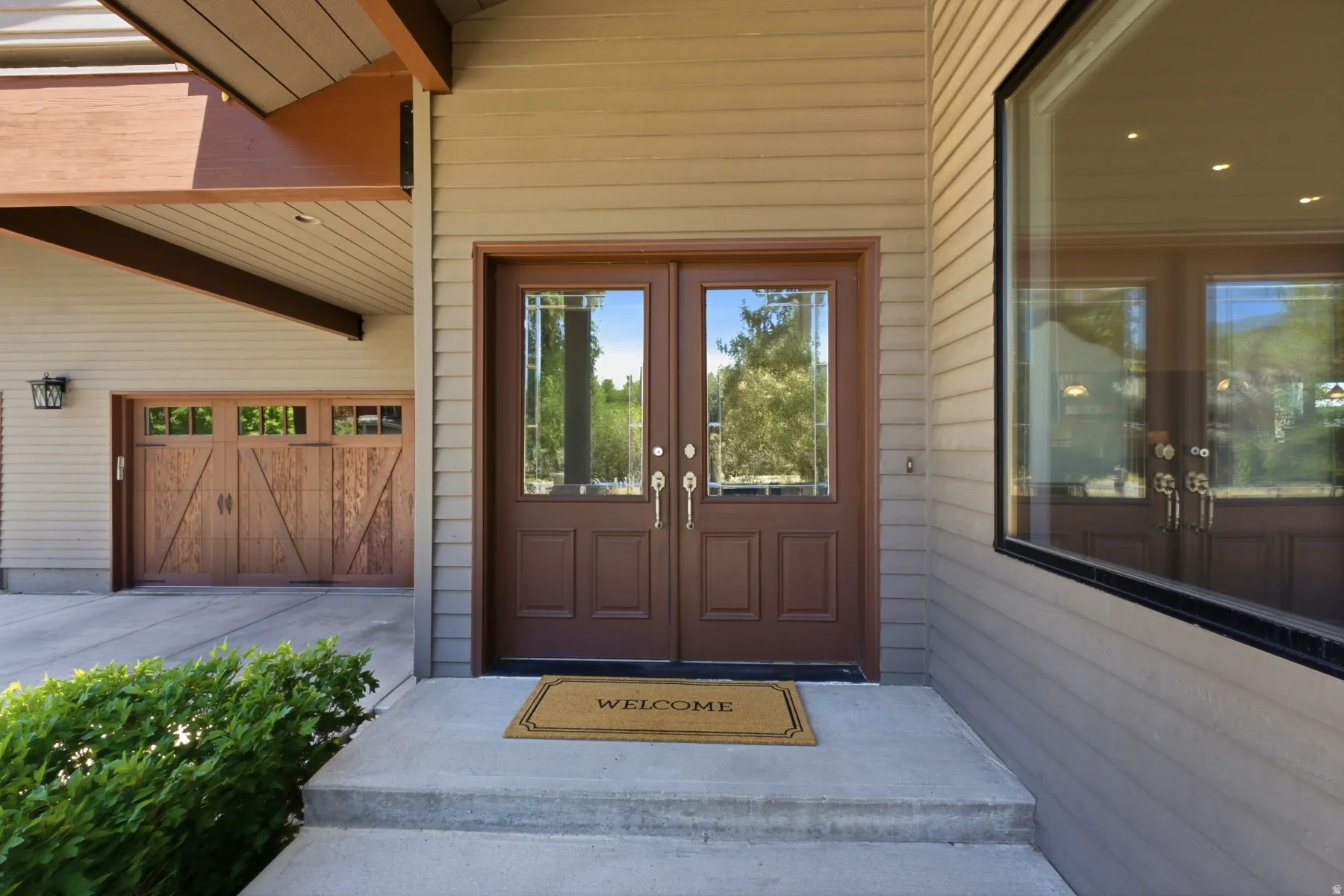 Exterior facade featuring horizontal siding, a double entry door with glass inserts, and an expansive window