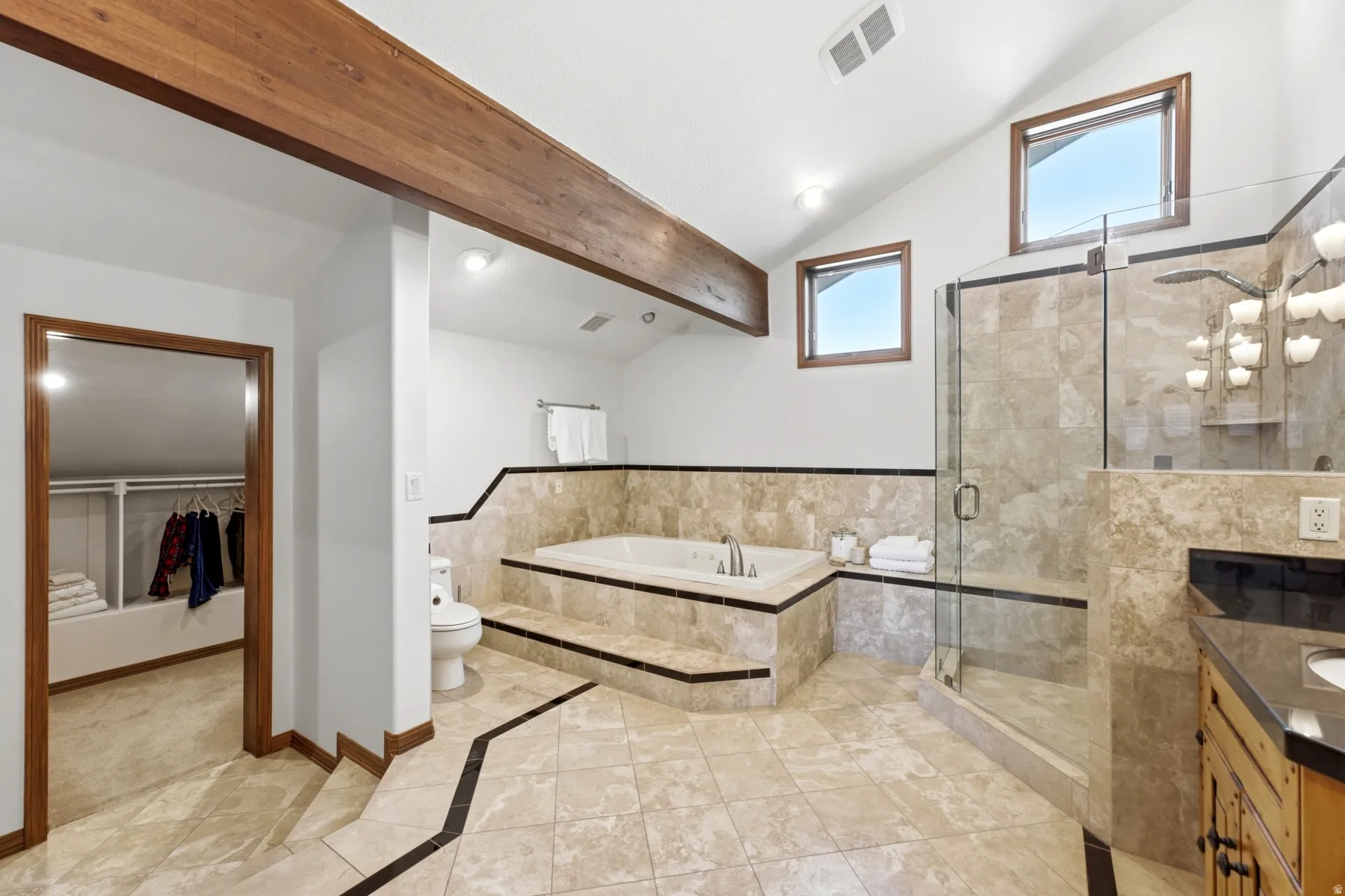 Vaulted ceiling bathroom featuring a glass-enclosed shower, built-in soaking tub, tile flooring, and wood-beam accents