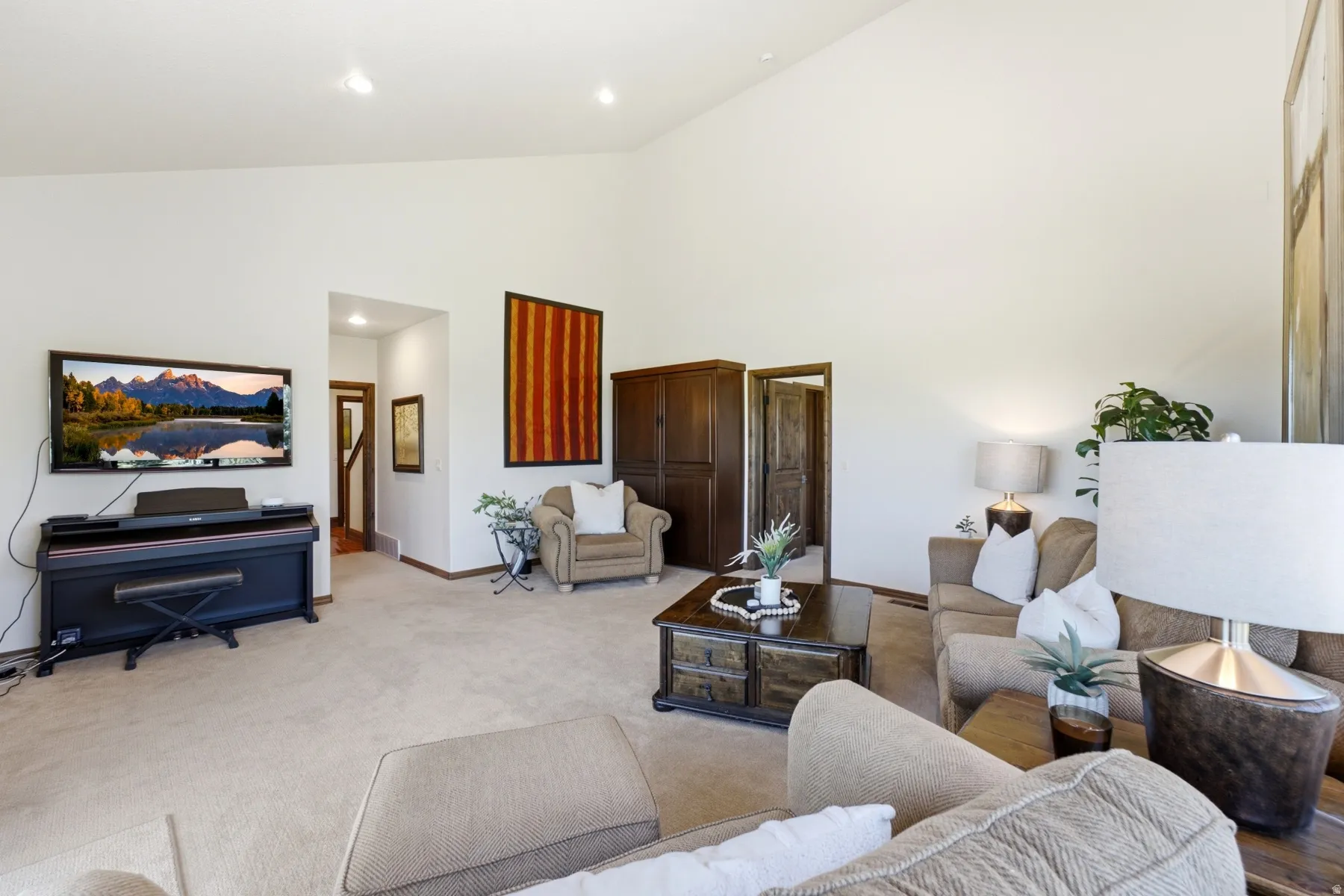 Spacious living area featuring a vaulted ceiling and neutral carpeting