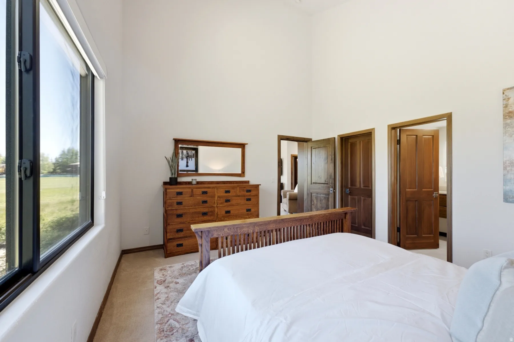 Expansive room featuring a large window, high ceilings, wood-finish doors, and light-toned flooring