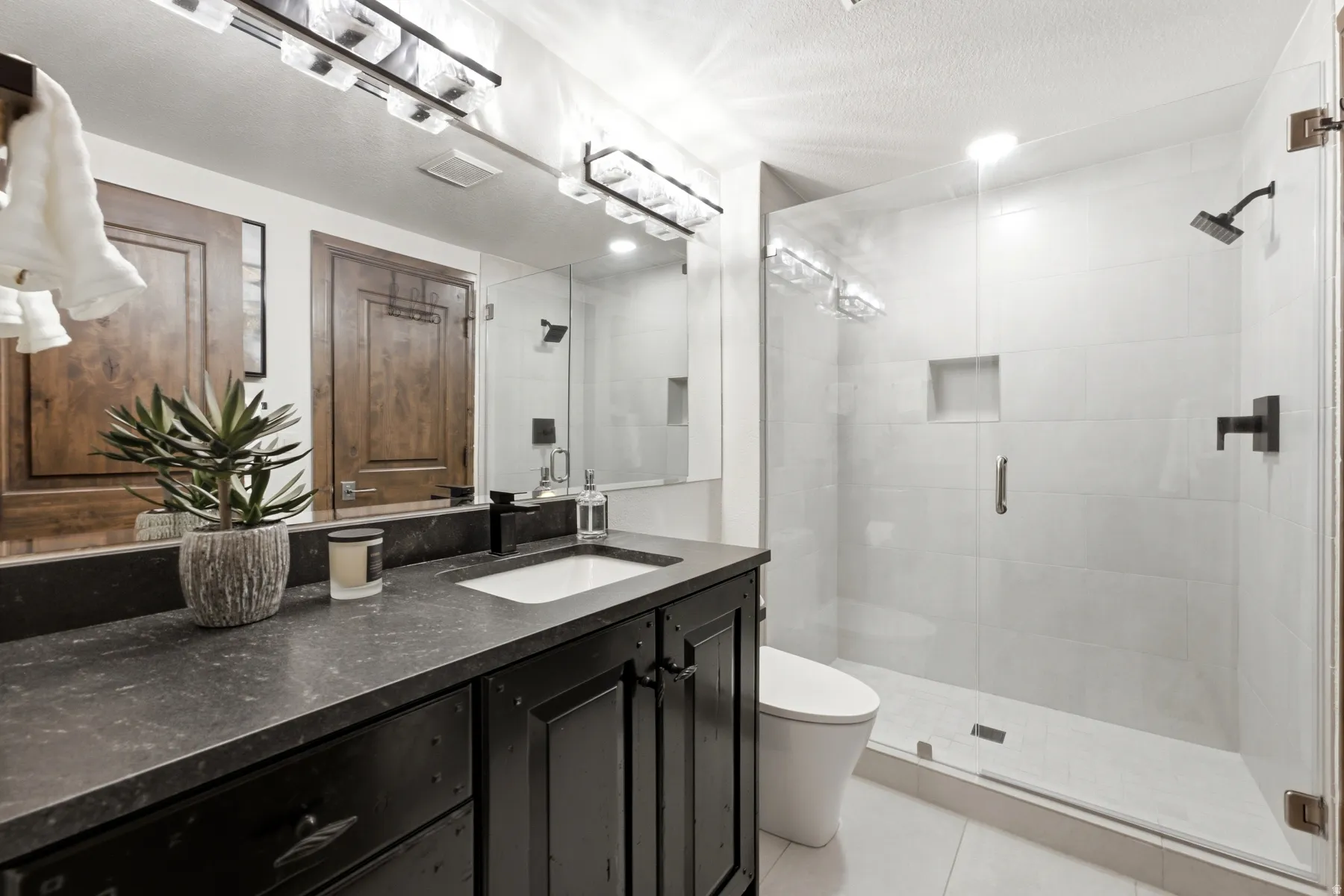 Modern bathroom featuring a single vanity with a dark countertop, a rectangular undermount sink, and a matte black faucet