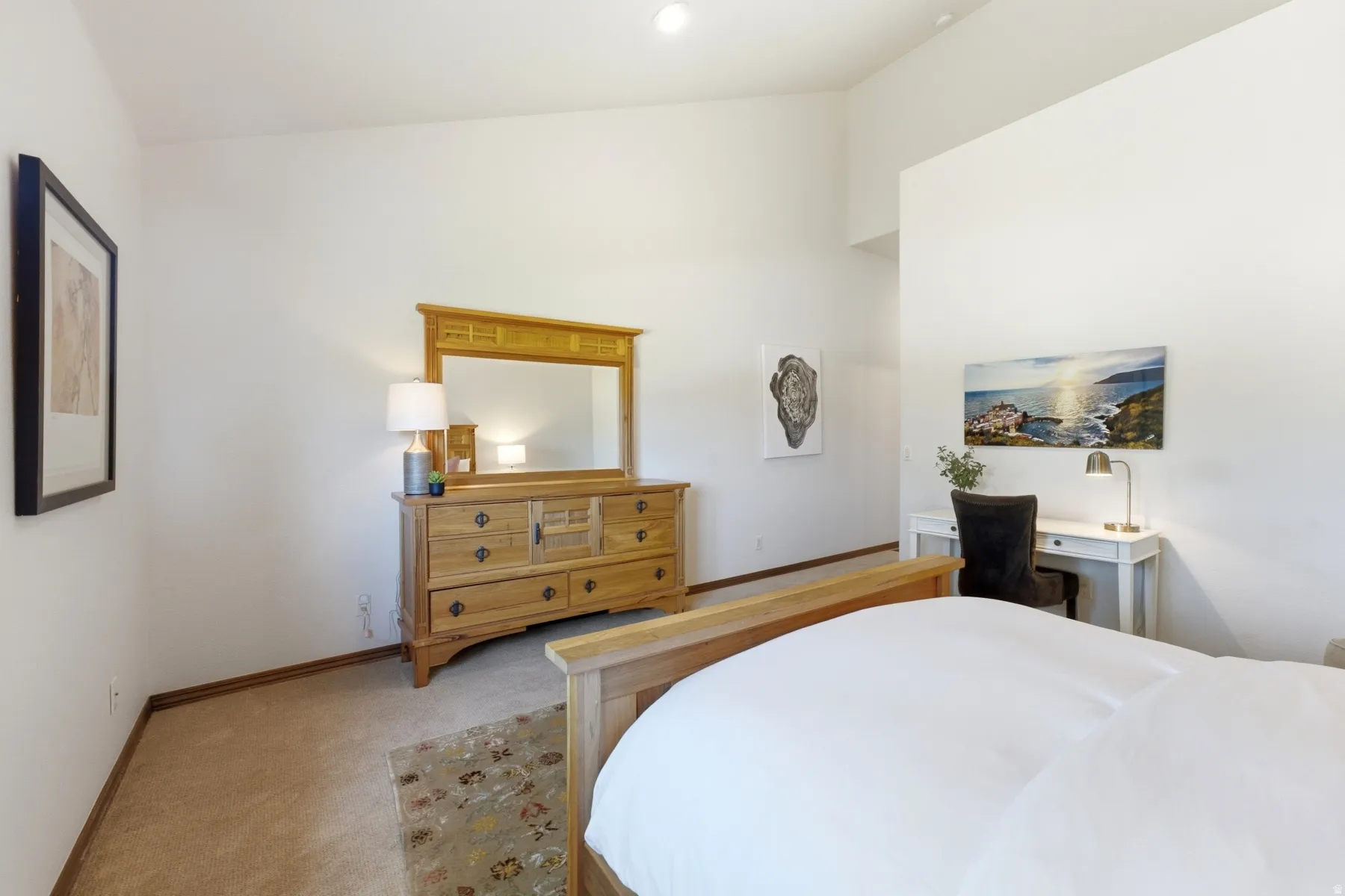 High vaulted ceilings, neutral wall tones, warm-toned carpeting, wood-finish baseboards, and natural light from an overhead fixture