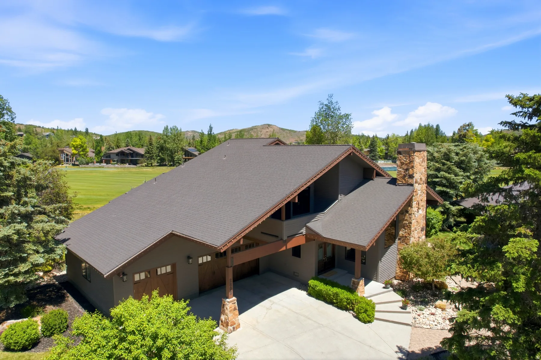 Contemporary exterior featuring multiple rooflines, a prominent stone chimney, and a covered entry with wood accents