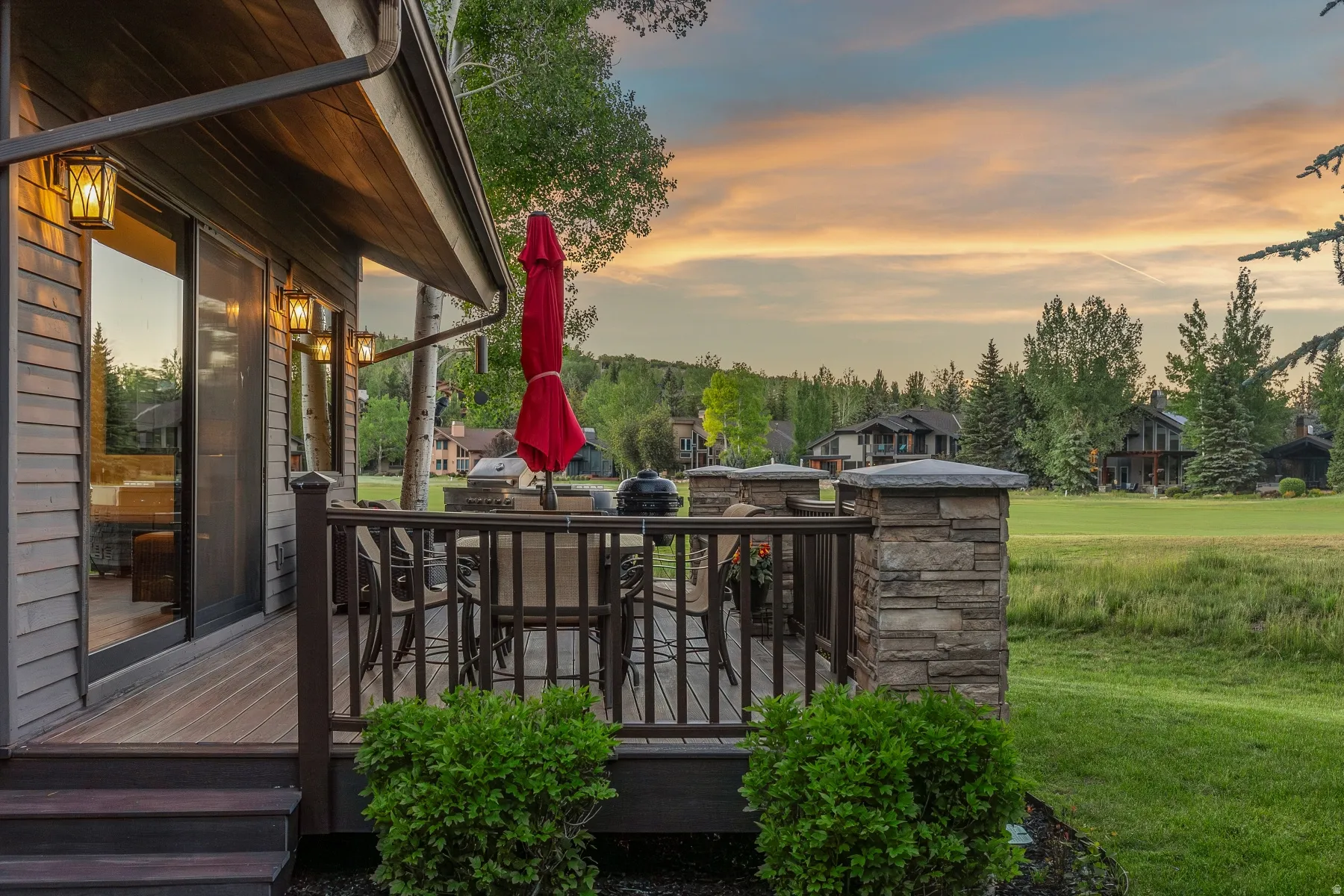 Expansive deck featuring composite decking and dark wood railings with stone-clad pillars