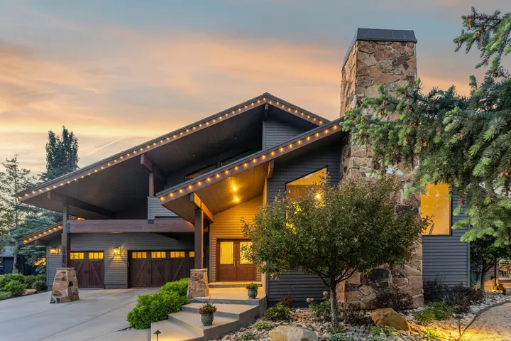 Contemporary exterior with dark horizontal siding, a prominent stone chimney, and an expansive covered entry