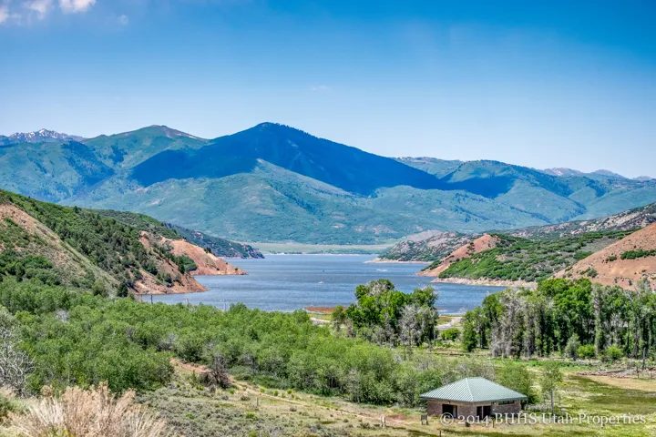Mountain landscape with a body of water, surrounded by verdant hills and a clear blue sky