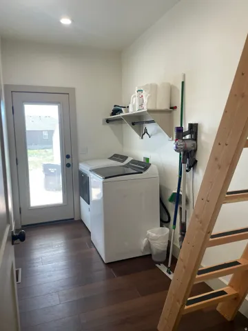Laundry area featuring wood-finish flooring, a white-framed exterior door with a window, recessed ceiling lighting, and a wall-mounted shelving unit