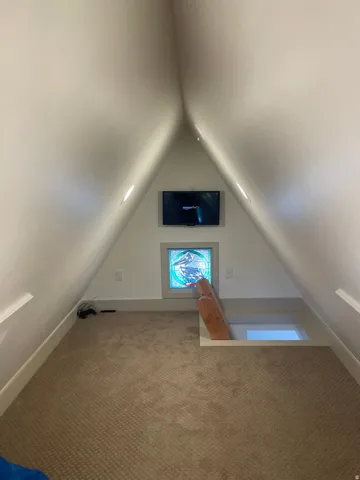 Carpeted attic space featuring sloped ceilings, a stained-glass window, and recessed lighting