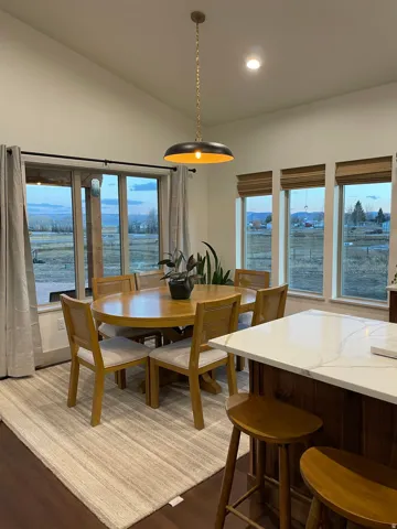 Dining area featuring wood-finish flooring, a large window with direct exterior access, and multiple windows with woven wood shades