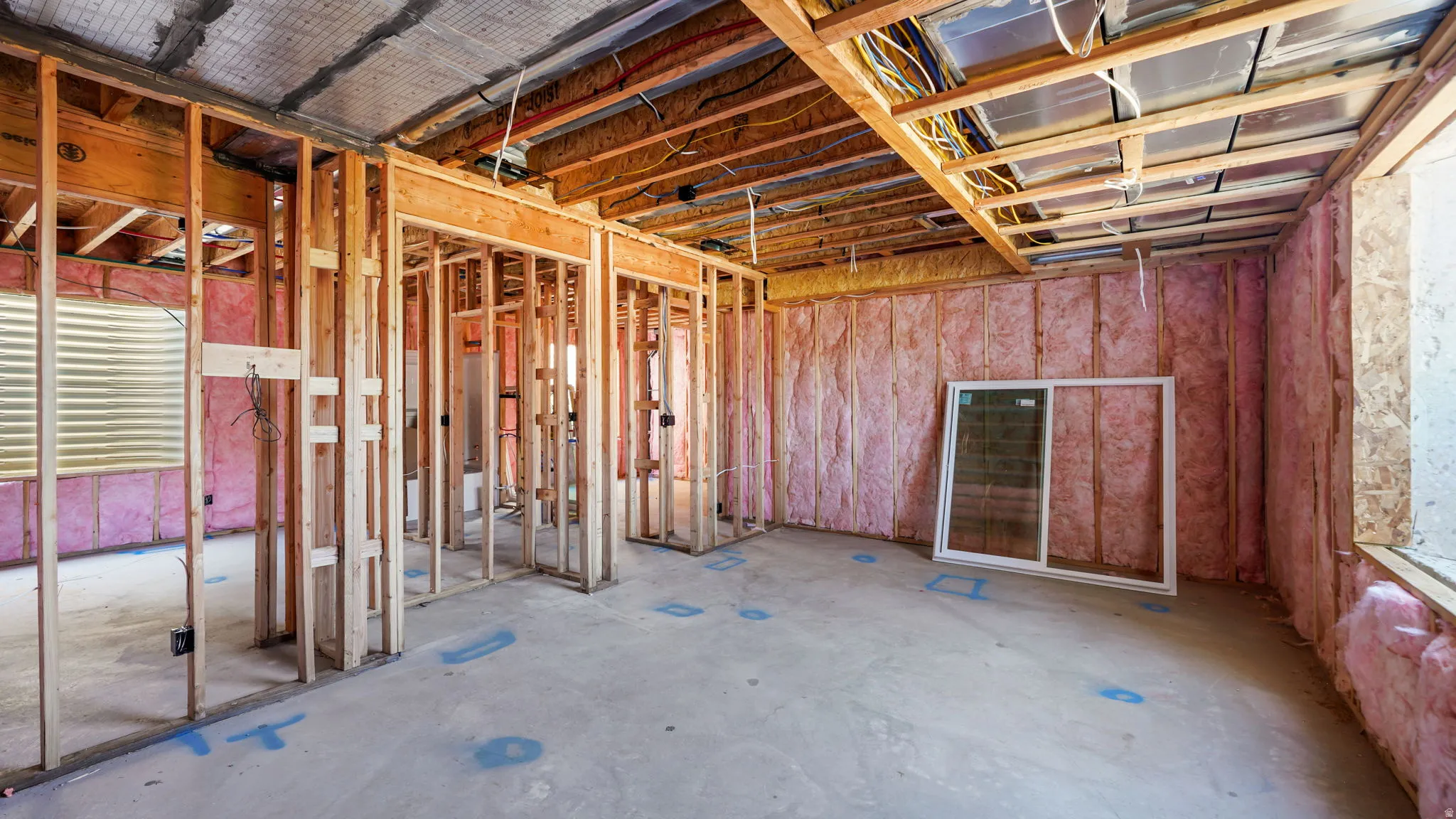 Framed interior with visible insulation, exposed ceiling joists, and a concrete floor