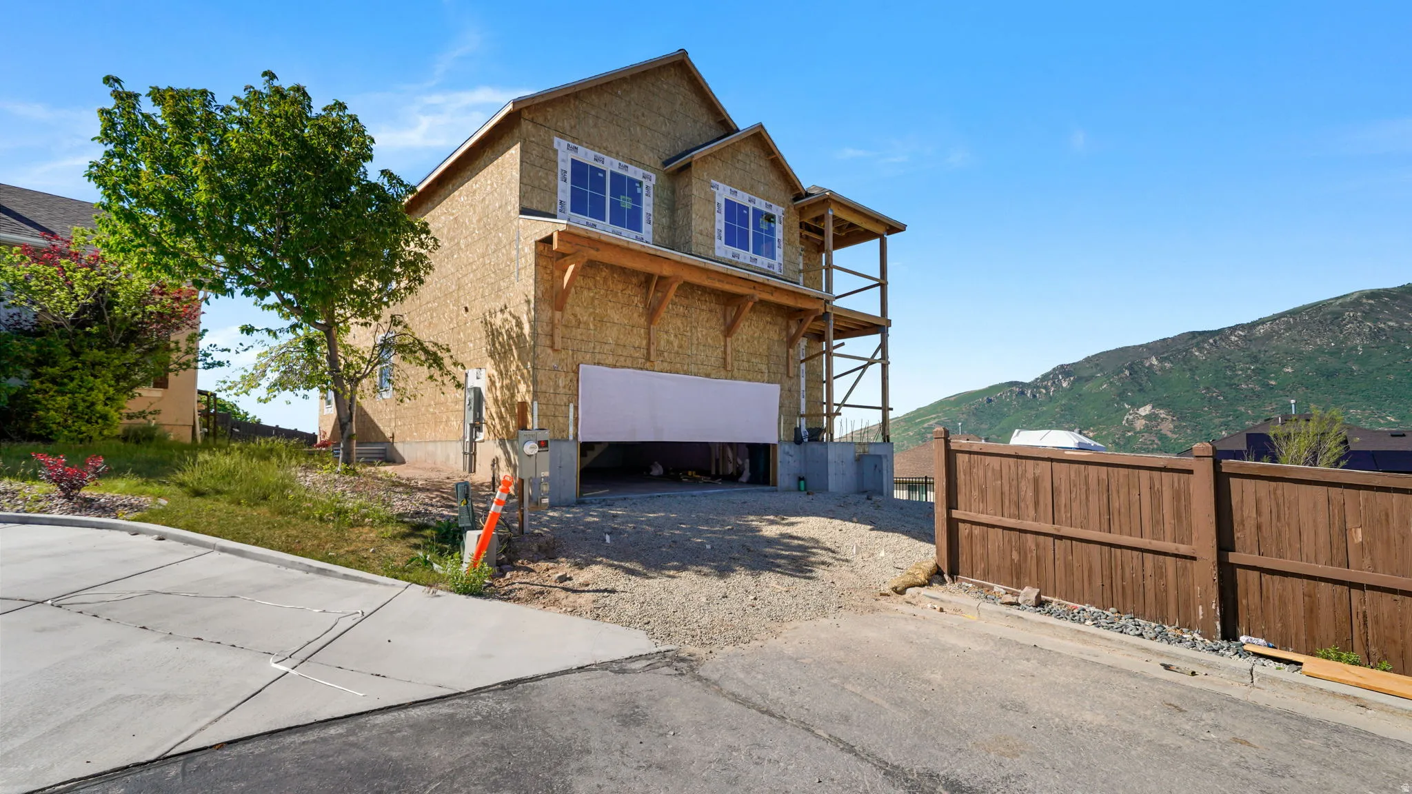 Two-story structure under construction featuring a prominent garage, second-story balcony framing, and visible window openings