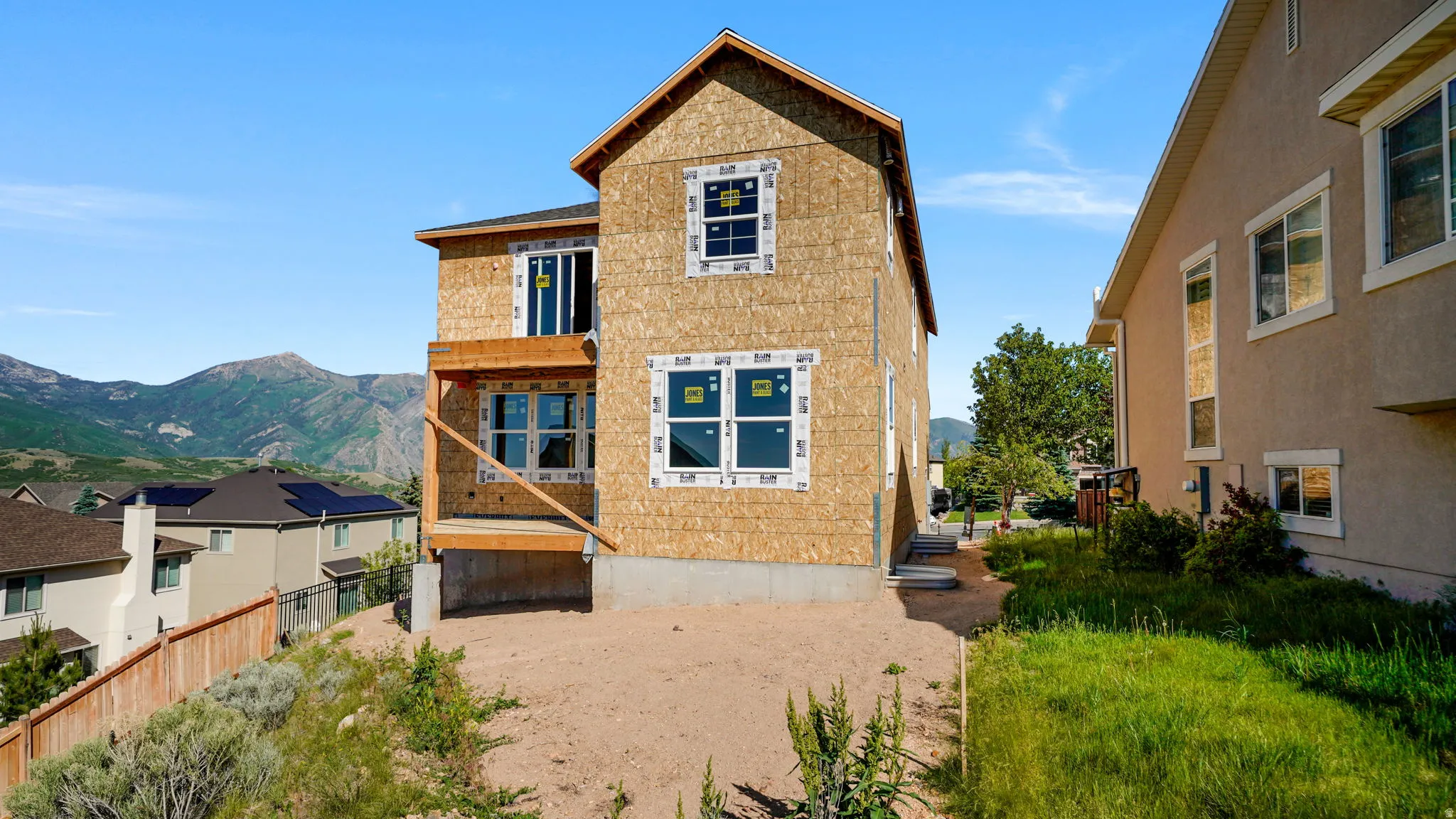 Two-story residential structure under construction, featuring exposed OSB sheathing
