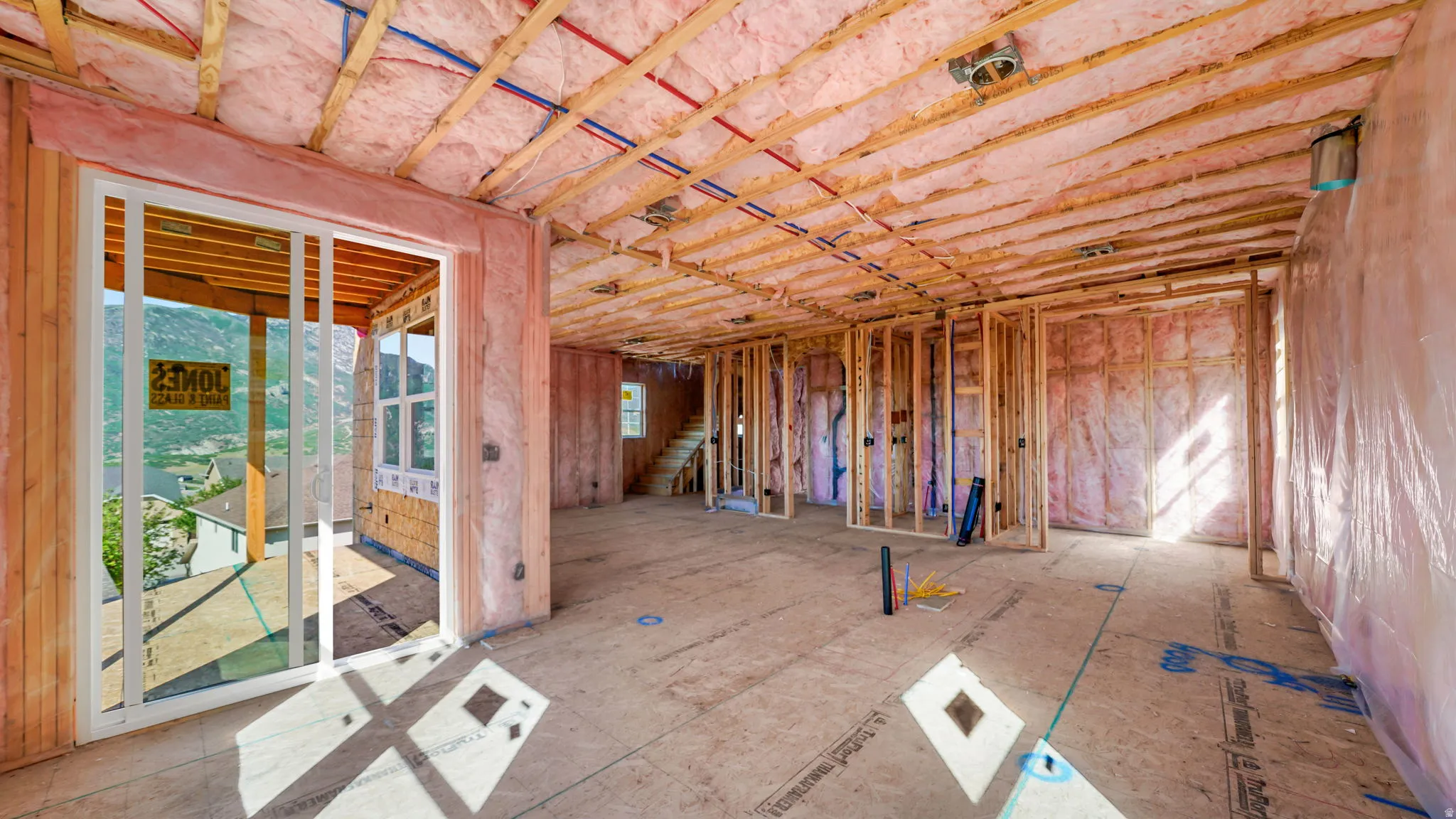 Framed interior space featuring exposed wood framing, ceiling joists, and pink insulation