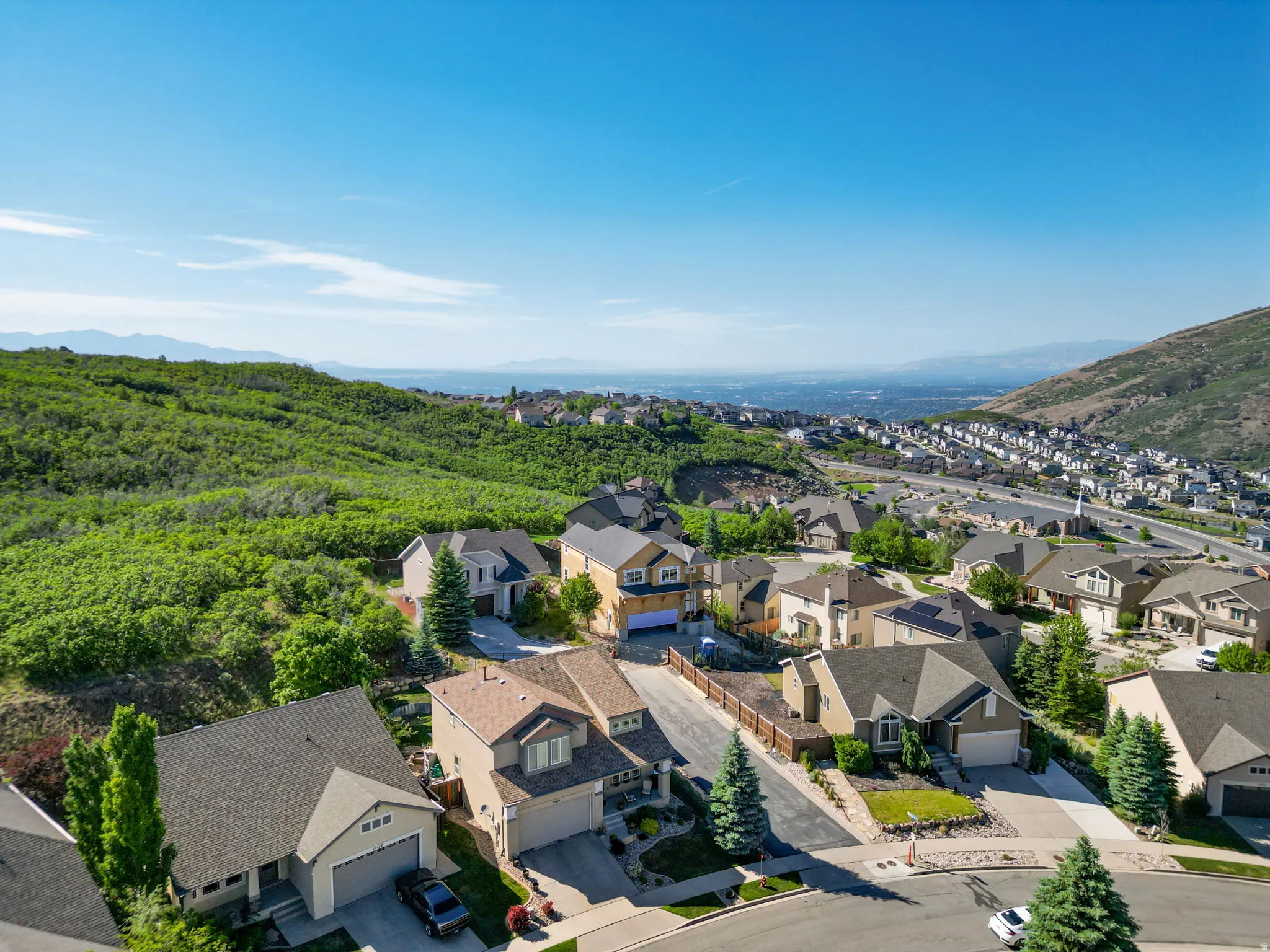 Residential neighborhood situated on a verdant hillside, featuring a variety of single-family homes with multi-car garages and mature landscaping