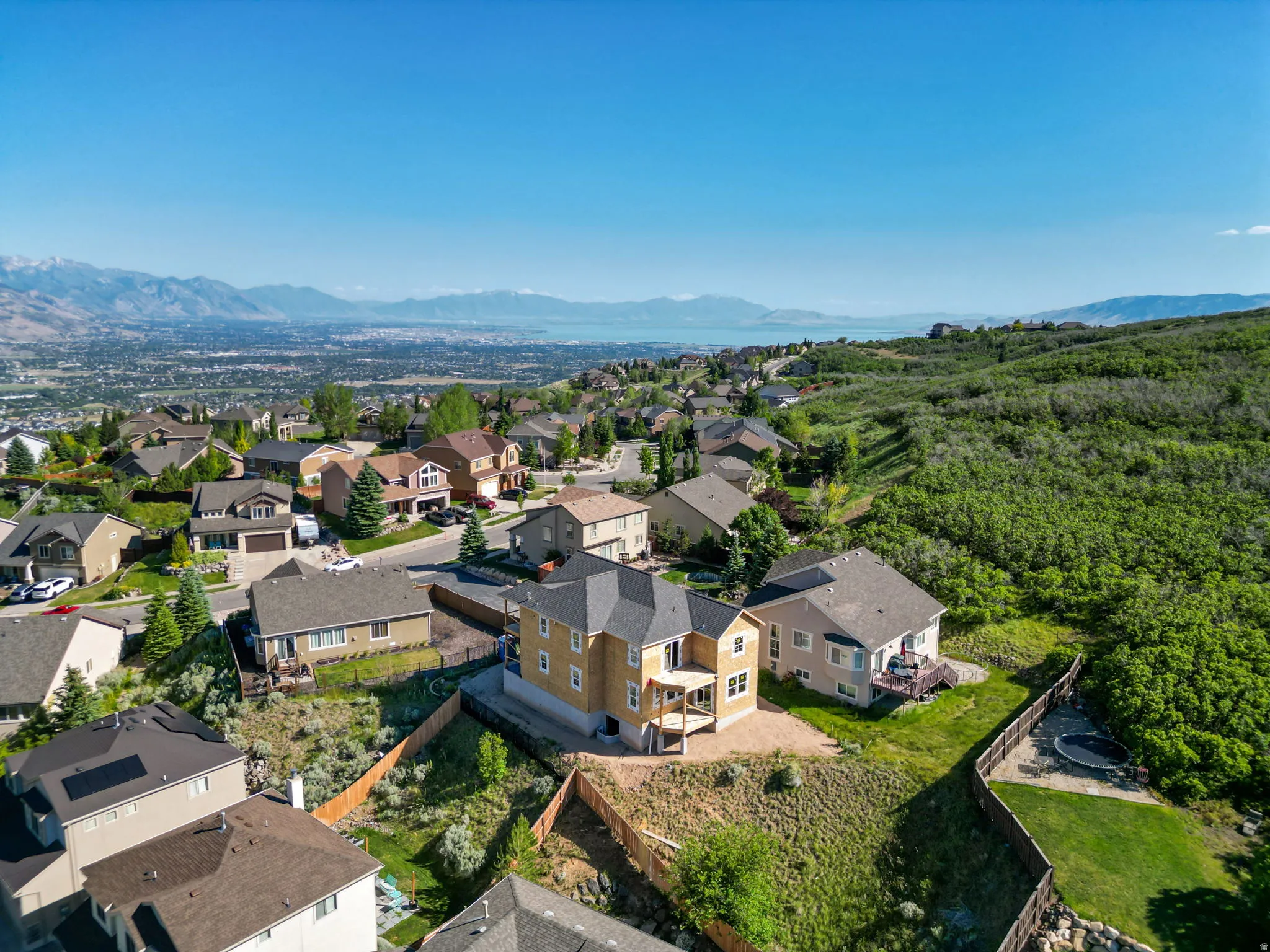 Elevated residential setting featuring a prominent home with an unfinished exterior facade and a walkout deck