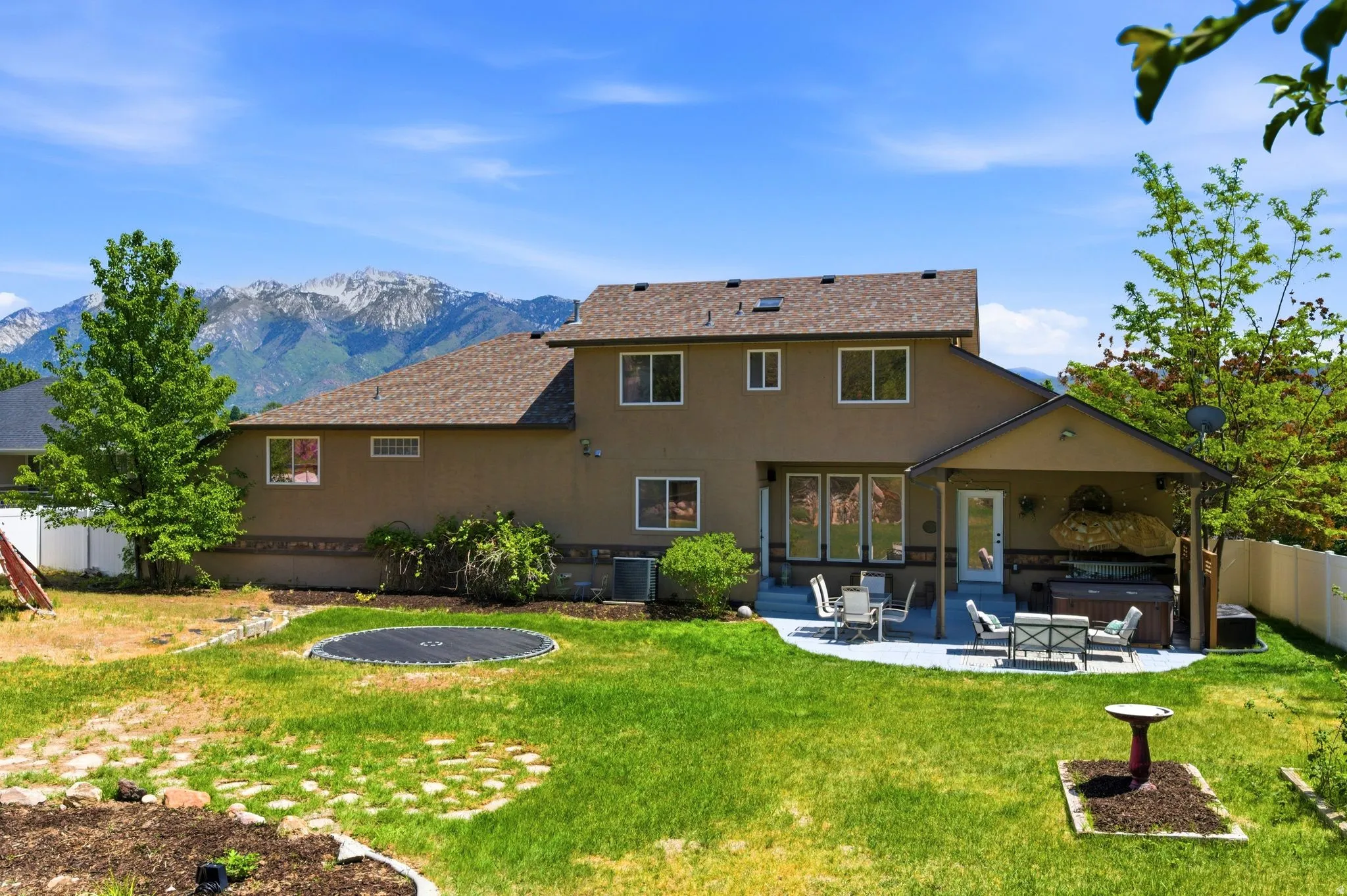 Expansive backyard featuring a covered patio, a spa, and a stone paver patio