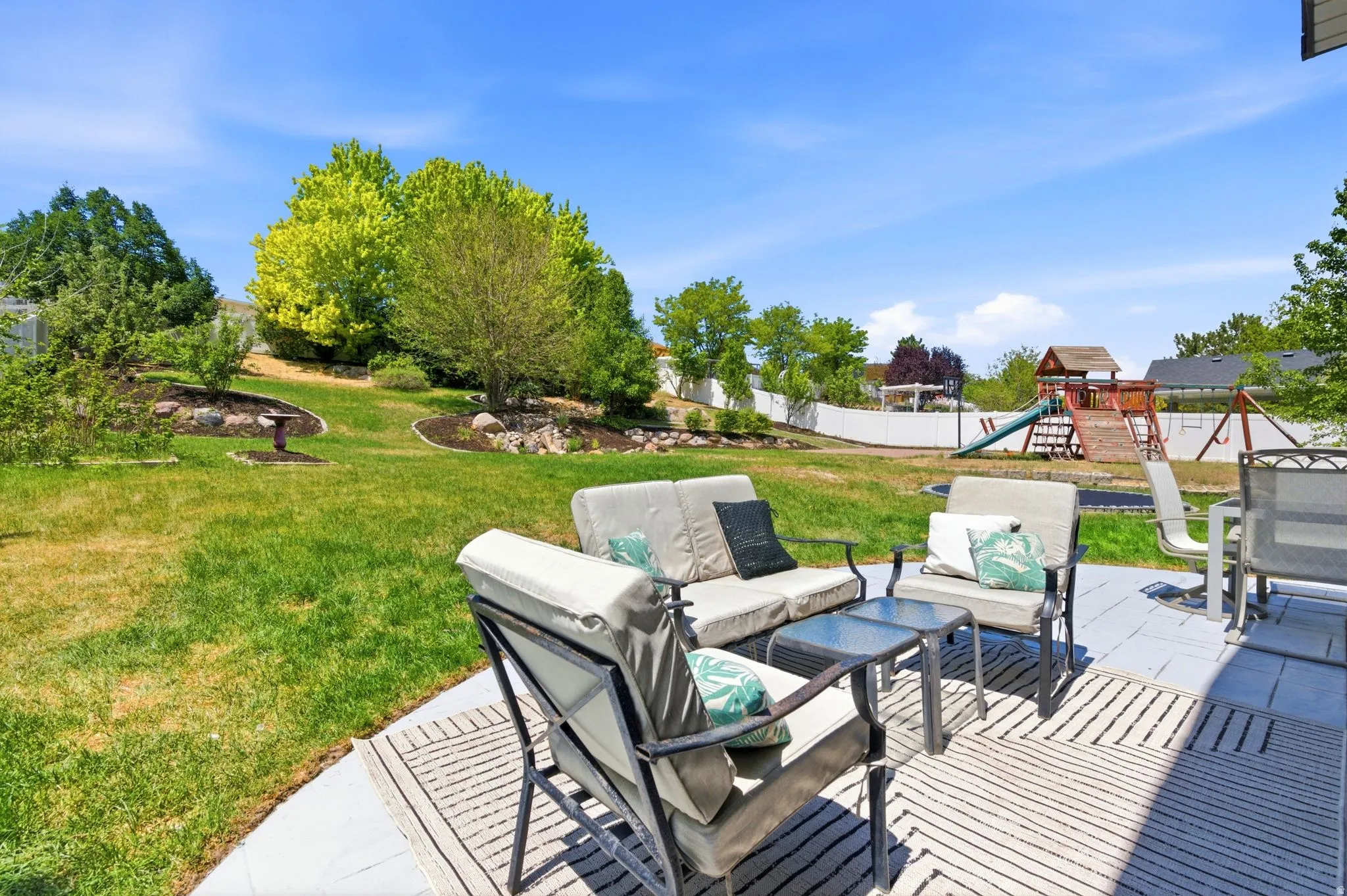 Expansive backyard featuring a concrete patio, a large grass lawn, and mature trees