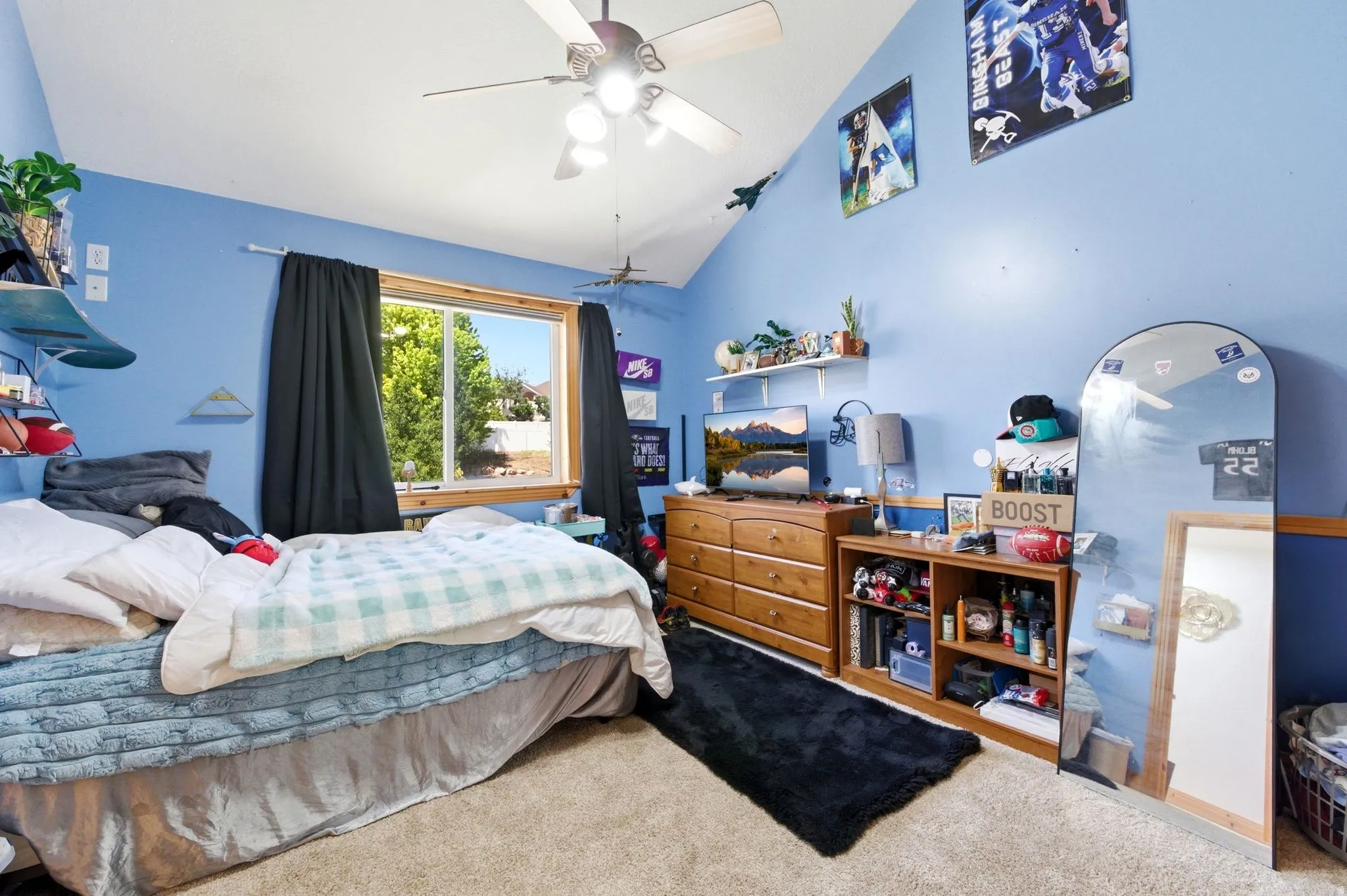 Carpeted room featuring a ceiling fan, sloped ceiling, and a large window with black-out curtains