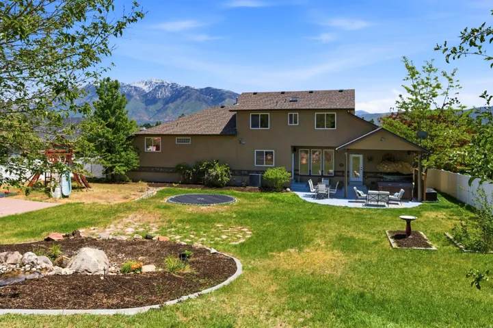 Expansive backyard featuring a covered patio, paved outdoor living area, and mature landscaping
