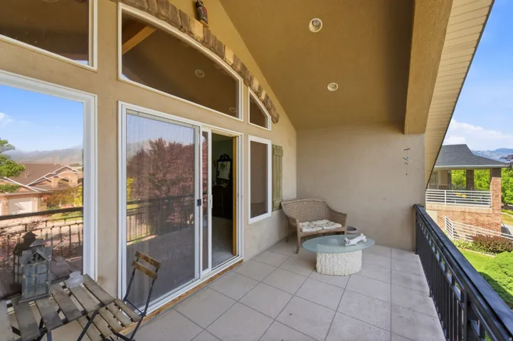 Expansive covered balcony featuring tile flooring and a black metal railing