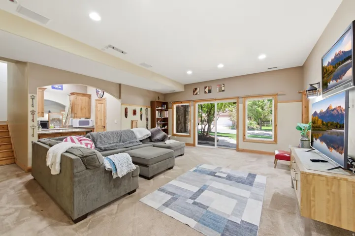 Spacious entertainment area with recessed lighting, an arched entryway, wood-finish built-in cabinetry, and wood-trim sliding glass doors
