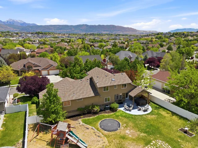 Rear exterior featuring a covered patio, paved outdoor living area, and a large manicured lawn